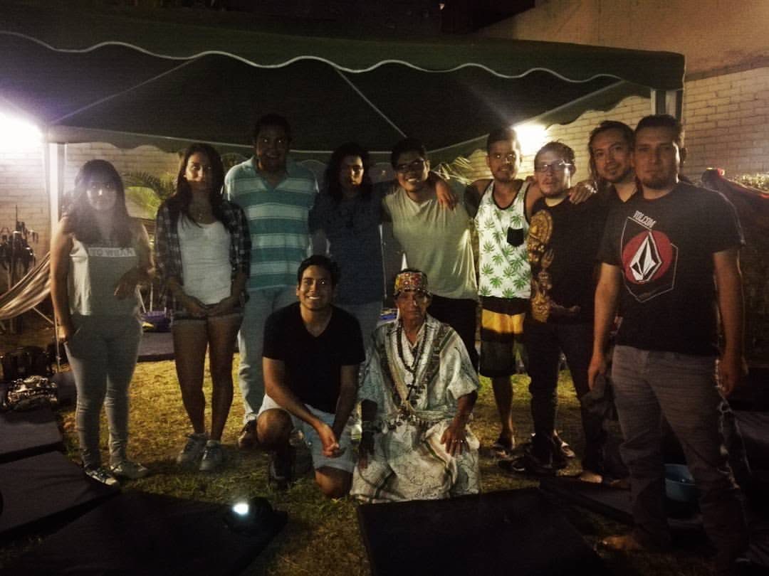 Grupo de personas reunidas de noche bajo un toldo